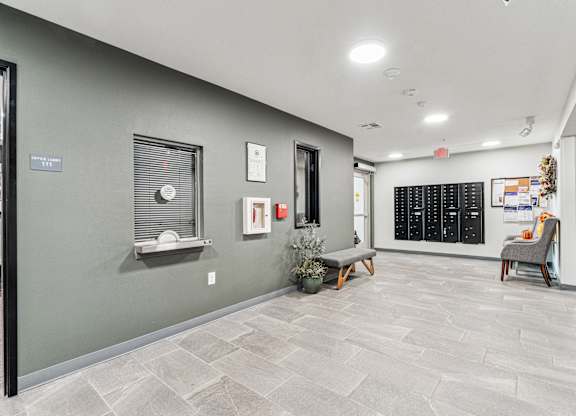 A hallway with a bench, a chair, and a wall with a calendar on it.