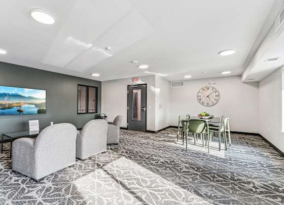 A spacious room with a television, chairs, and a dining table.