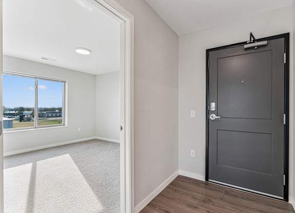 A room with a black door and a carpeted floor.