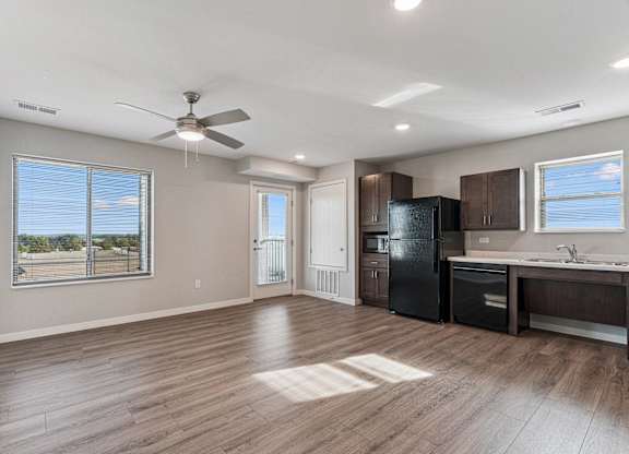 A spacious kitchen with dark wood cabinets and a black refrigerator.