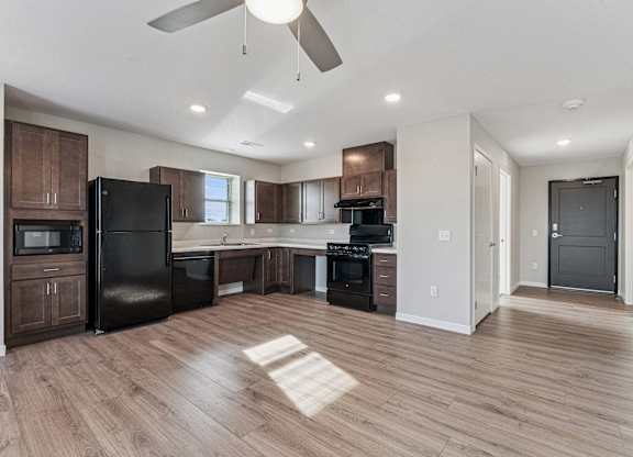 A modern kitchen with dark wood cabinets and a black refrigerator.