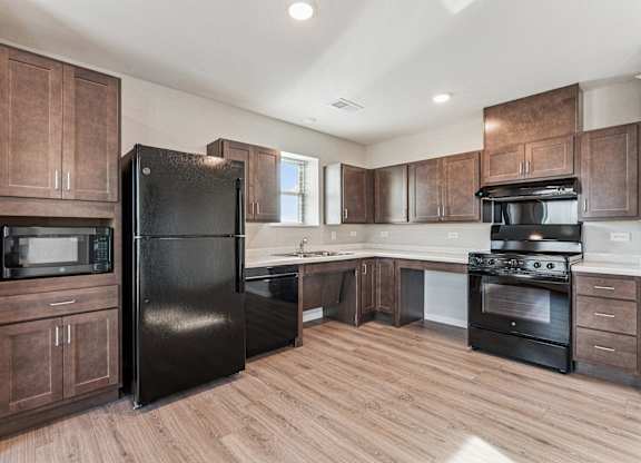 A kitchen with wooden cabinets and black appliances.