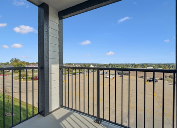 A balcony with a black railing overlooks a parking lot.