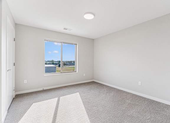 A room with a carpeted floor and a window showing a blue sky.