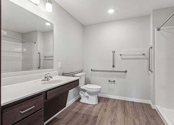 A white bathroom with a toilet, sink, and a walk-in shower.
