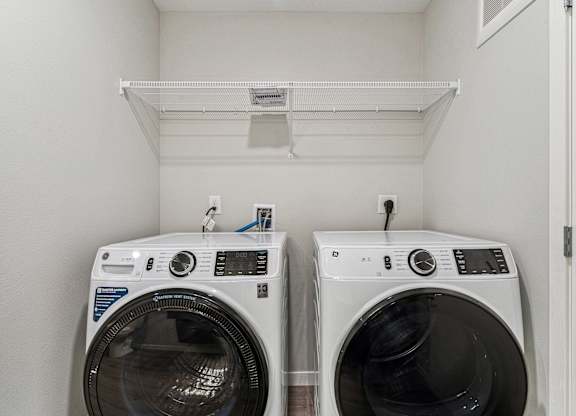 Two front load washing machines in a small laundry room.