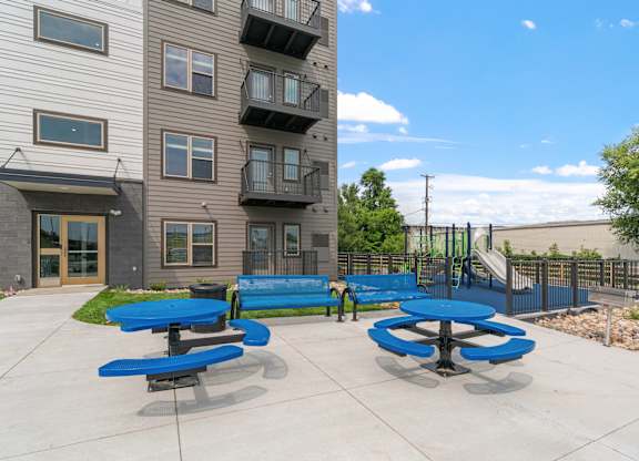 outdoor patio with blue tables and benches in front of 5240 Apts