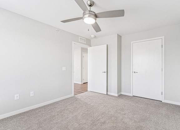 A room with a ceiling fan and carpeted floor.
