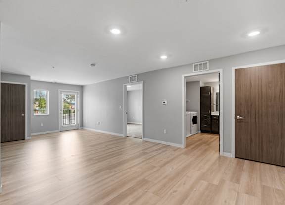 a renovated living room with a hardwood floor and a door to a kitchen