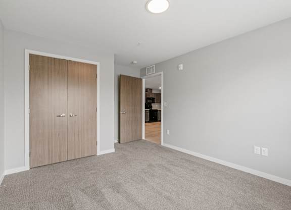 bedroom with closet opening to living room and kitchen areas