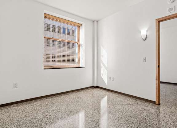 A room with a window covered by wooden blinds and a door.