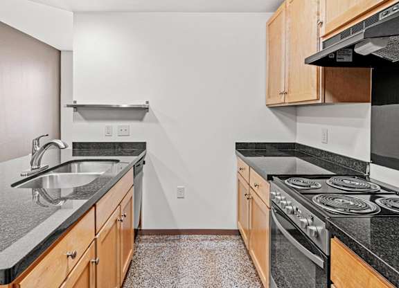 A kitchen with a black counter top and a stove.