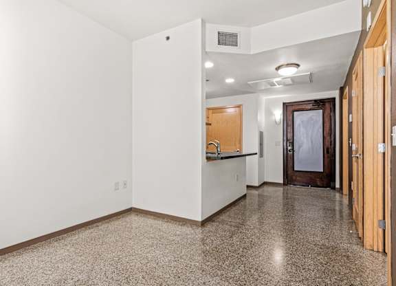 A hallway with a brown floor and white walls.
