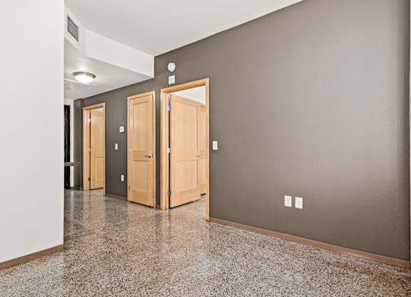 A hallway with three doors and a tiled floor.