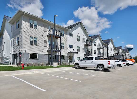 A white truck is parked in a parking lot in front of a building.