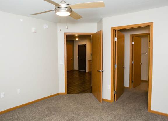 A room with a ceiling fan and carpeted floor.