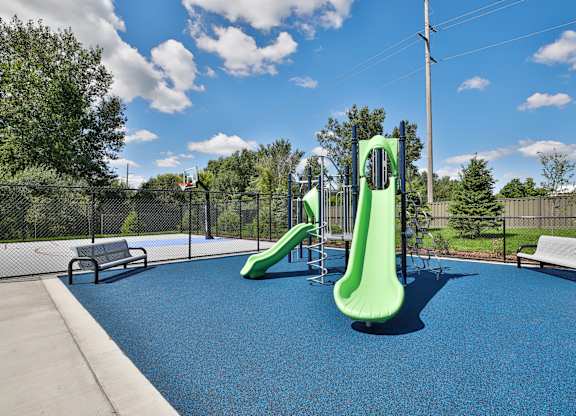 A playground with a blue surface and a green slide.