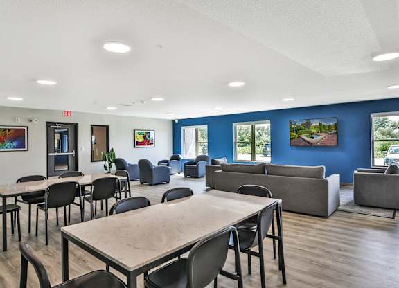 A room with tables and chairs and a blue wall.
