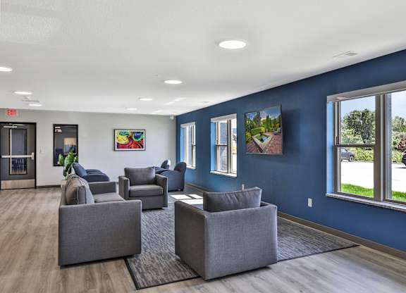 A spacious waiting room with grey couches and a view of the street outside.