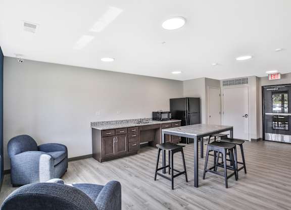 A kitchen area with a bar and chairs.
