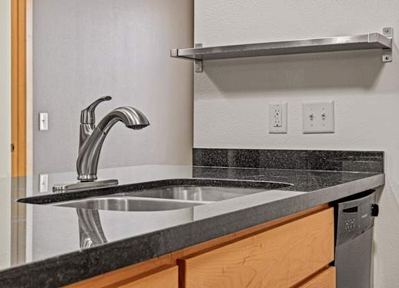 A modern kitchen with a black granite countertop and a stainless steel faucet.