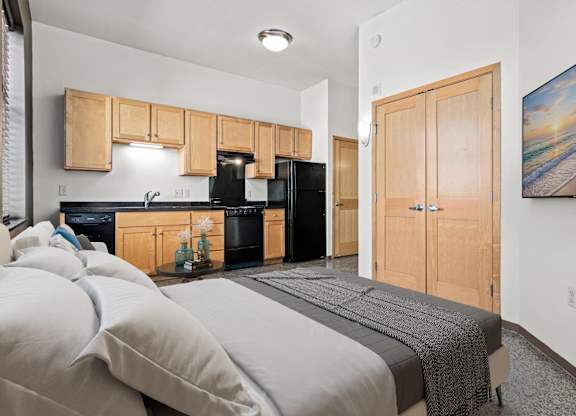 A bedroom with a bed, a fridge, and a painting on the wall.