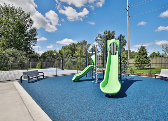 A playground with a blue surface and a green slide.