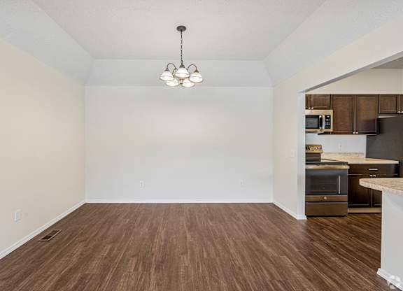 A room with wooden floors and a chandelier hanging from the ceiling.