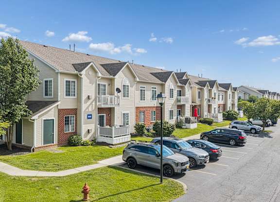 A row of houses with cars parked in front.