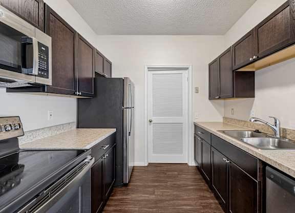 A kitchen with dark brown cabinets and a black refrigerator.