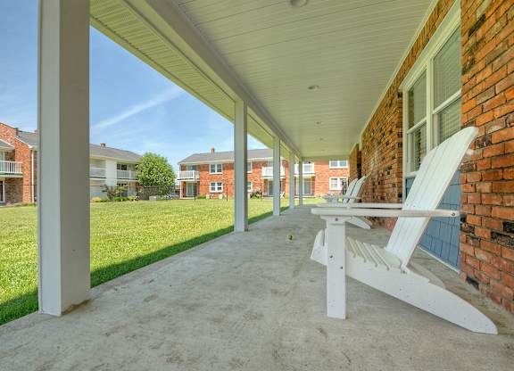 A white chair is on a concrete porch.