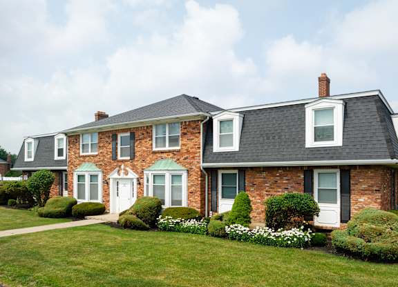 A large house with a white door and windows surrounded by a green lawn.