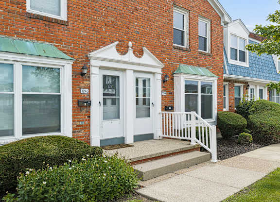A red brick house with a white door and windows.