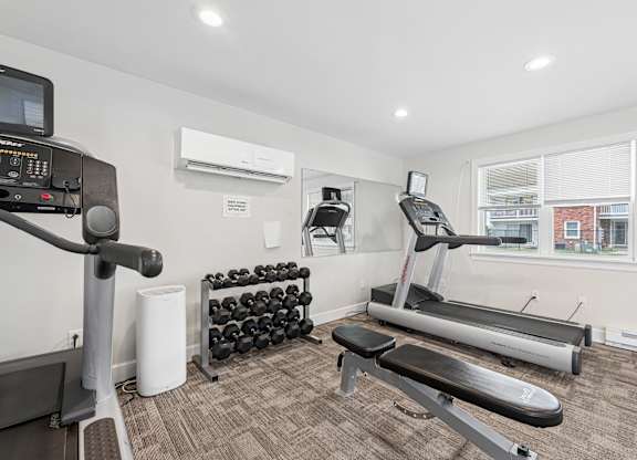A home gym with a treadmill, weights, and exercise equipment.