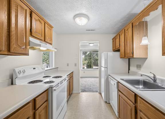 A kitchen with white appliances and wooden cabinets.