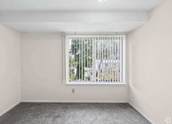 A room with a window covered by a white blind.