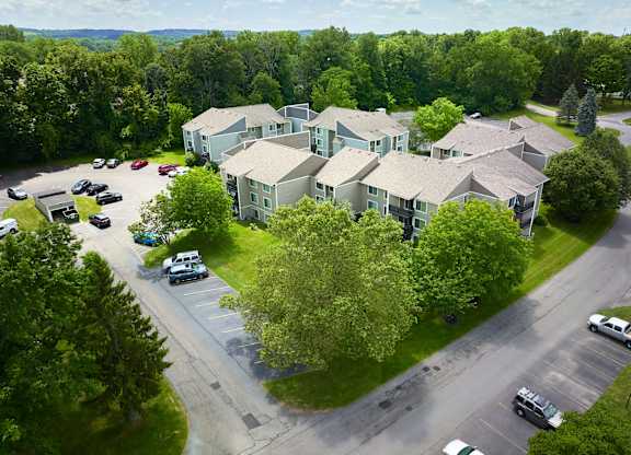 A bird's eye view of a parking lot with cars and a building in the background.