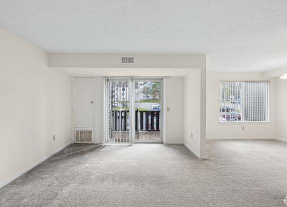 A spacious, empty room with a carpeted floor and white walls.