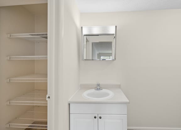 A white bathroom with a sink and a mirror.