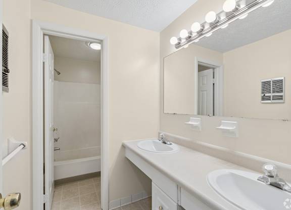A bathroom with a sink, mirror, and shower.