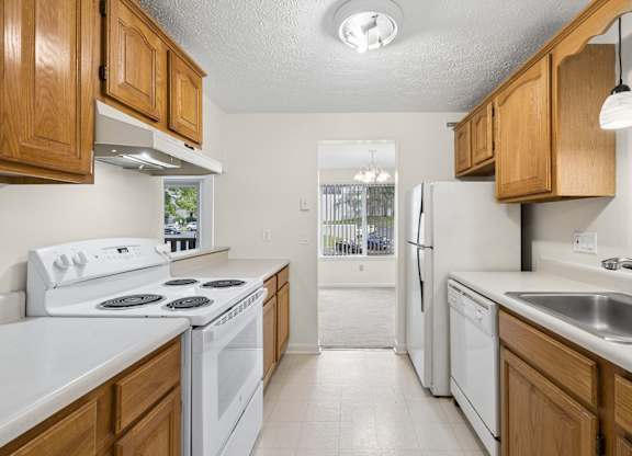 A kitchen with white appliances and wooden cabinets.