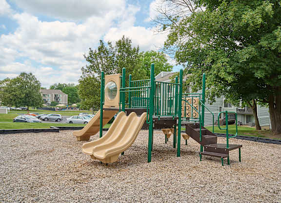A playground with a green slide and a brown slide.