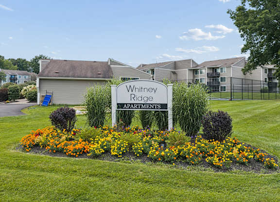 A sign for Whitney Ridge Apartments is in front of a building.
