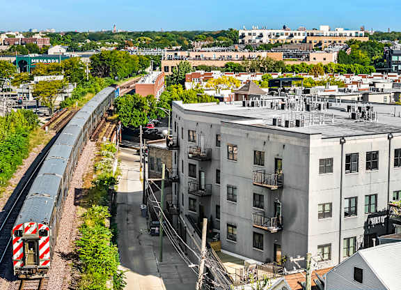 A train is coming down the tracks in a city.