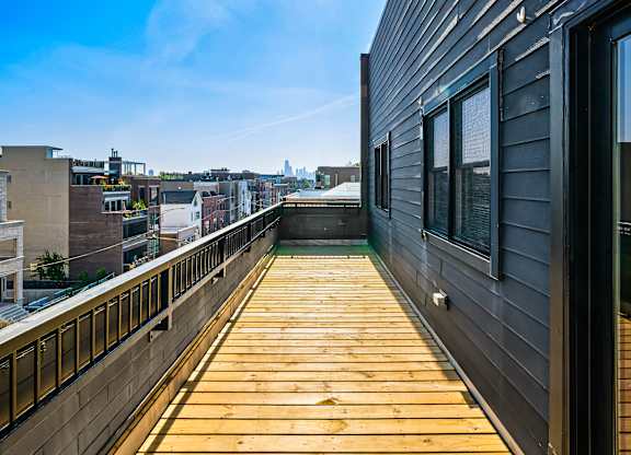 A wooden deck with a railing and a building with a window in the background.