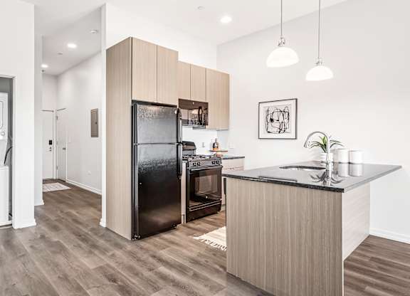 A modern kitchen with a black fridge and wooden cabinets.