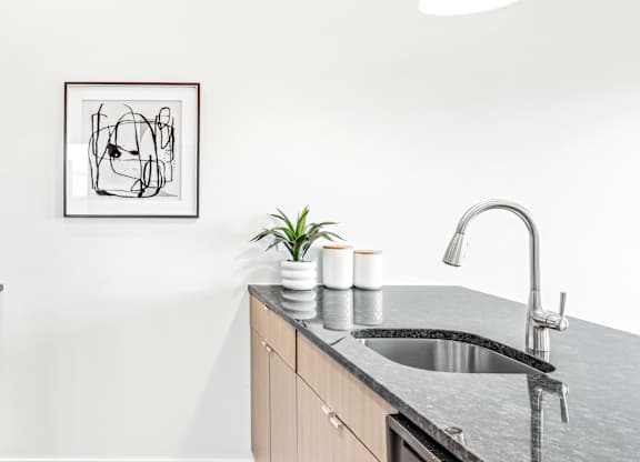 A modern kitchen with a sink and a framed abstract art piece on the wall.