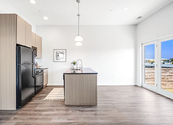 A modern kitchen with a black refrigerator and wooden cabinets.