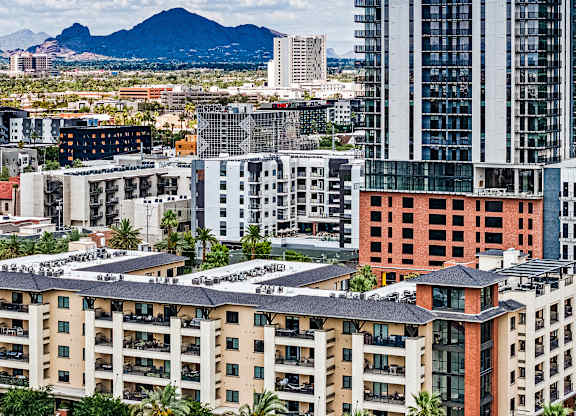 A cityscape with buildings of various designs and a mountain in the background.