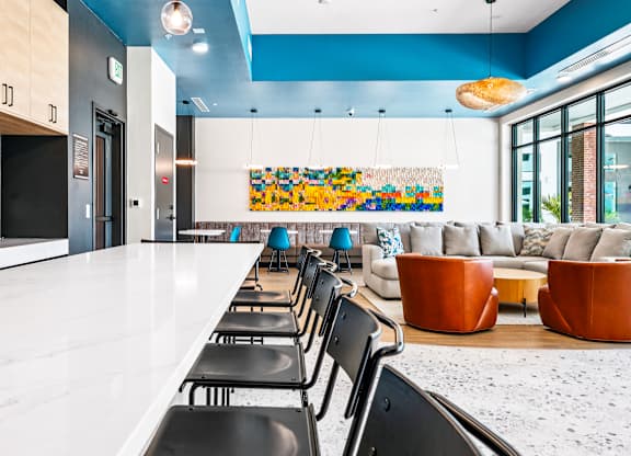 A long white table with black chairs is in the foreground of a room with blue walls.